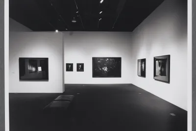 Photographs of different sizes line the gallery walls. A bench is in the center of the gallery for viewing the works. 
