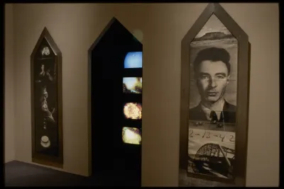 Two large wooden canvases with black and white historical photos hang on either side of doorway with four colorful screens. 