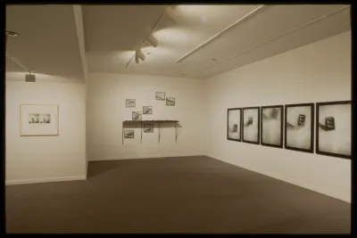 Blurry black and white framed action photos hang in three groups on gallery walls: one on left, eight in middle, and five on right.