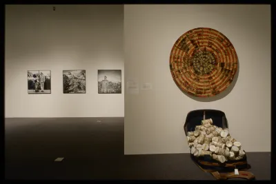 Photographic portraits of artist Tseng Kwong Chi hang on the gallery wall just behind a multi-media installation by Sung Ho Choi. 