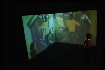 In a dark gallery, 2 screens in a corner.