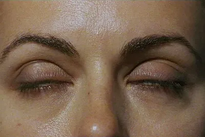 Video still captures a close up view of a woman mid-blink, exploiting the texture of her fair skin and dark eyebrows