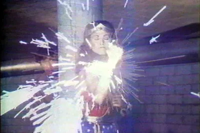 Video still of wonder woman running in a hallway with fireworks in the foreground.