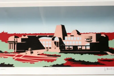 A print of a pink building sitting in a red and green landscape. A gradient blue sky sits on the horizon.