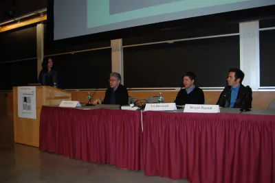 Three people sit at a table at the MIT List Center Wasserman Forum.