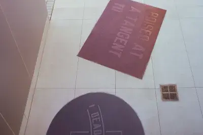 Photo of Lawrence Weiner's Dead Center includes pieces of Gray, red, and black granite that read &quot;Dead Center&quot; and &quot; Poised At A Tanget To&quot;.