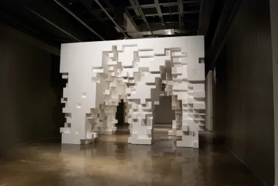Cube-like structure made from white Styrofoam blocks and blocks removed to form irregular-shaped arch openings and footings