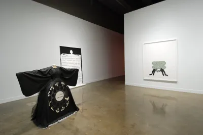 A black dress with large sleeves and a rounded skirt is shaped into the fashionof an old rotary style phone where the sleeves become handles and the skirt has round number icons.