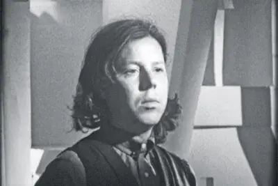 A black and white still of a woman looking off screen.