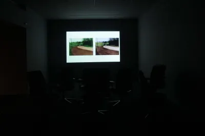 In a dark room, a large projection illuminates the back wall