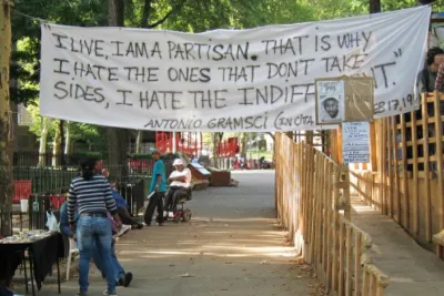 A white fabric banner hanging reads "I live, I am a partisan, that is why I hate the ones that don't take sides. I hate the indifferent. Antonia Gramsci"
