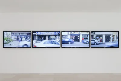 Four screens are placed in a row with a street scene playing on all of the screens.