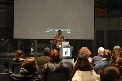 People are seated and listen to a speaker.