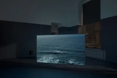 Video installation showing an ocean wave on a screen in a dim gallery.
