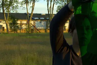 A person holds a red light gel sheet to their face.