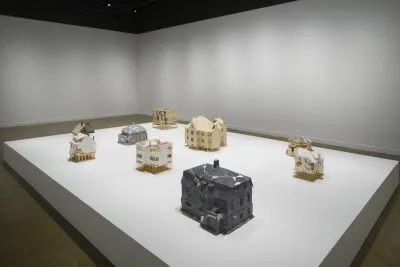 7 small sculptures of different homes on a large pedestal.