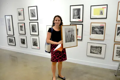 A woman poses with a framed artwork.