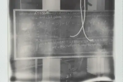 A chalkboard is photographed on a blurry black and white Polaroid.