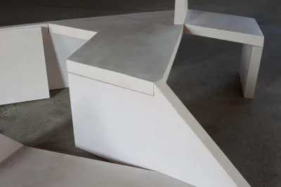 A sculpture of white geometric wooden shapes is on the floor