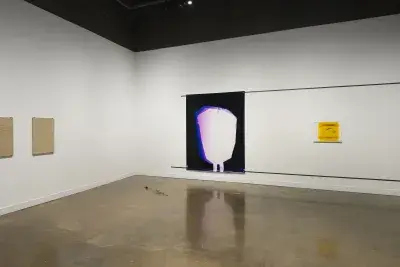 A corner space, two clay tablets on left wall, a large abstract print and a small yellow and black print on wall to the right