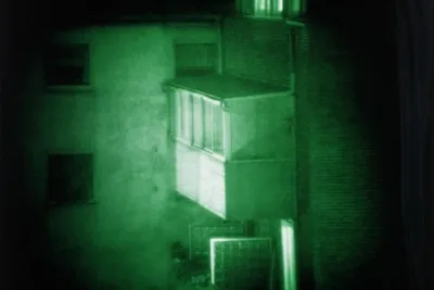 Night view of a covered balcony outside of a brick building, glowing in green light