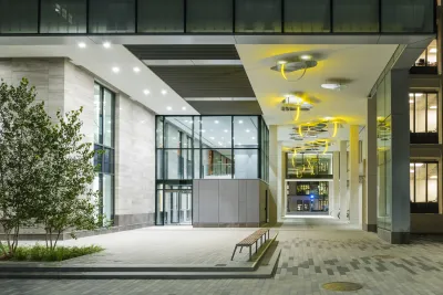 Olafur Eliasson's Northwest Passge hangs in the pedestrian path on the side of a building complex.