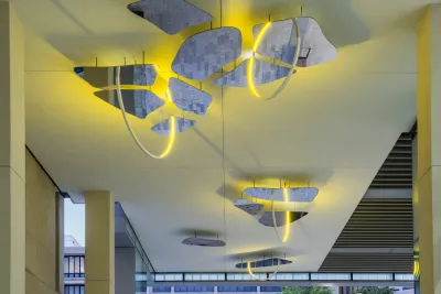 An installation by Olafur Eliasson features three yellow LED hoops on a ceiling.