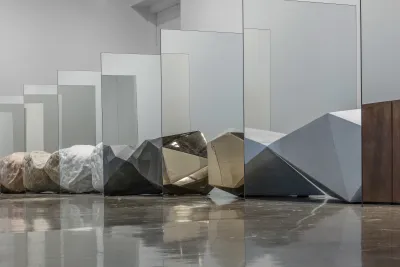An installation including large rocks placed between sheets of mirror.
