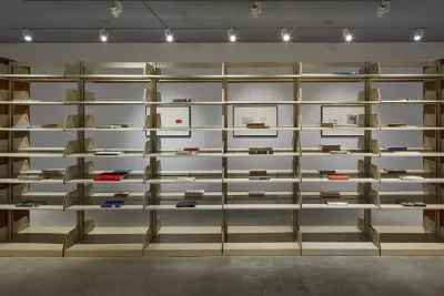 A large wooden shelving unit sculpture is featured in a gallery space.