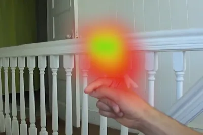 A person holds their finger out with a bright orange light at their finger tip.