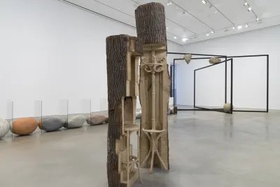 Two wooden logs with carvings are featured in a gallery space.