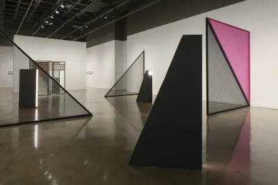 Installations consisting of clear glass, plastic and purple triangular shapes are in a gallery.