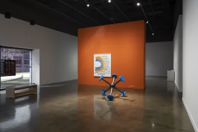 An orange wall divides the galleries featuring Sable Elyse Smith's &quot;Coloring Book 33&quot;