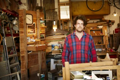 Artist Ethan Hayes-Chute is pictured in front of a wooden studio cabin space with open drawers.
