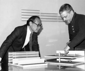 Black and white image of I.M. Pei and Scott Burton look over a model of the List Center building 