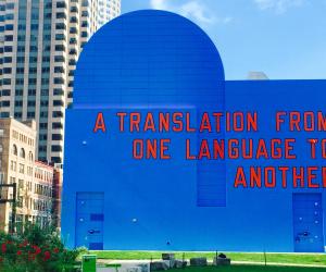 A blue mural on the side of a building reads "A translation from one language to another."