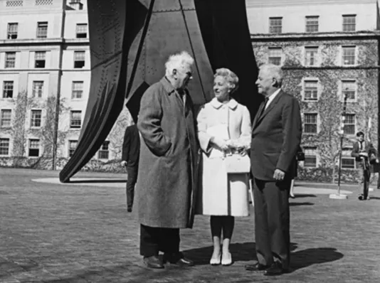 Black and white photo of three people standing in front of a steel sculpture by Alexander Calder.