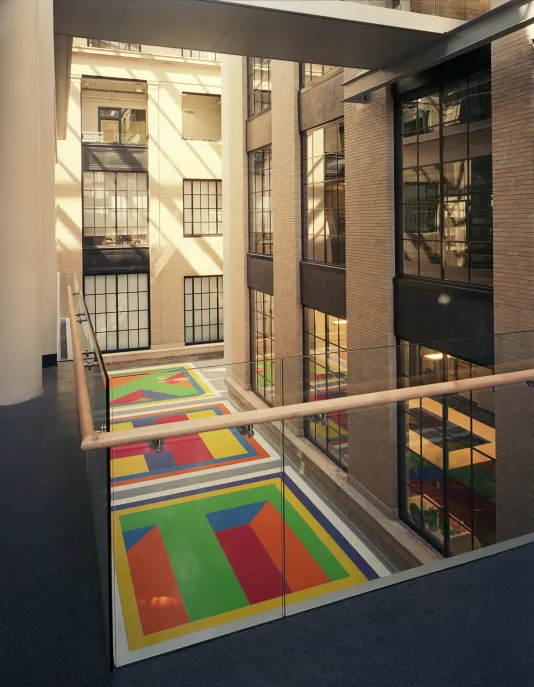 Lewitt's colorful Terrazzo floor including red, green, orange, purple, and yellow tiles inside a building with high ceilings.