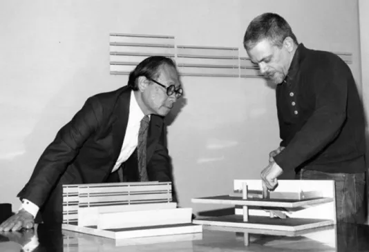 Black and white image of I.M. Pei and Scott Burton look over a model of the List Center building