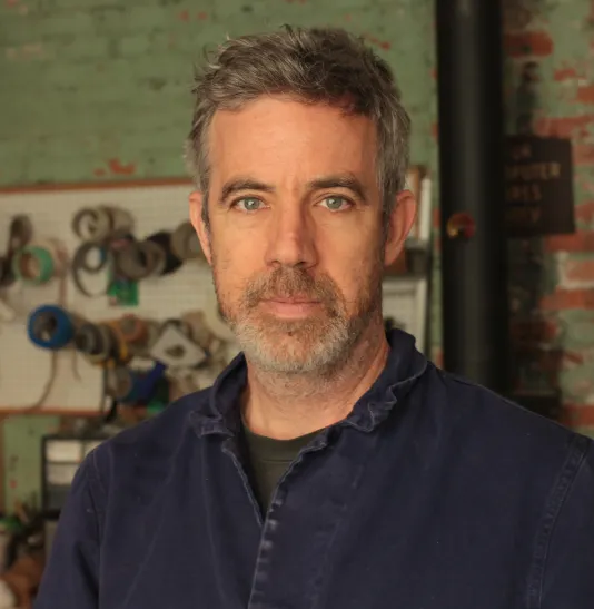 Headshot of Corin Hewitt wearing a navy dress shirt.