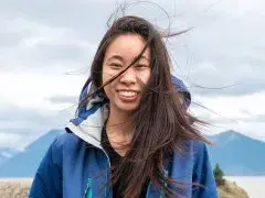 Portrait of a student guides wearing a blue jacket with a mountains in the background.