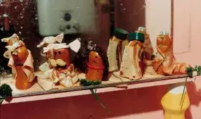 Sausages lines along a mirror dressed up in other clothing such as bread and deli meat.