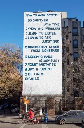 White mural on a building with blue text outlining the steps for working better