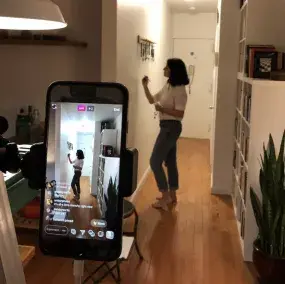 A phone recording a girl painting on a hallway wall.