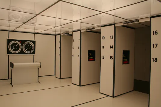 Installation view of a modern white room with black borders and numbers lining the right wall.
