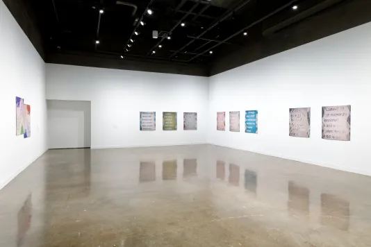 Installation view featuring eight colored inkjet prints on vinyl on the right wall and two rectangular prints on the left wall.