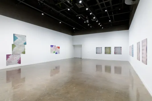 Installation view featuring three inkjet prints on vinyl on the left, right, and back gallery walls. 