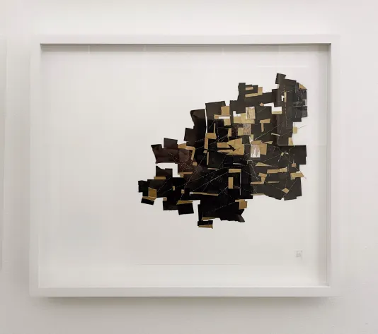 Photograph of a framed artwork featuring a brown and black abstract paper collage on the right side of the page.