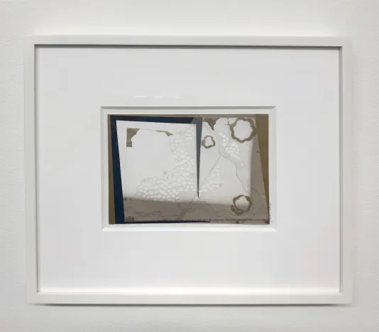 Photograph of a framed collage print that has small cut out circles, wavy lines, and brown edges.