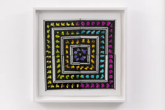Photograph of a framed artwork featuring black and white squares with small dabs of paint lining the edges of each in yellow, pink, blue, green, and purple.